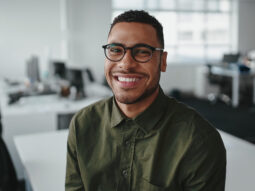 Friendly and smiling young african american professional businessman looking at camera in modern office